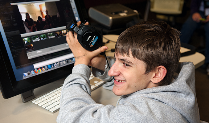 A student uses headphones to work on a computing project