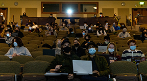 Students in an auditorium with a projector running.