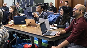 Attendees of SIGSCE laugh and smile while using computers.