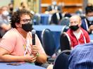 A participant sitting at a table speaks into the mic to ask a question during a session at Tapia 2023.