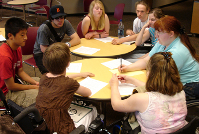 Photo of a large group of students collaborate on a team project at a table 