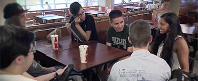 Students sit around a table in the cafeteria.