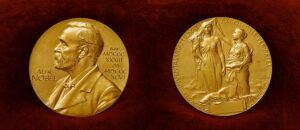 photo of both sides of gold nobel prize medal on red velvet background